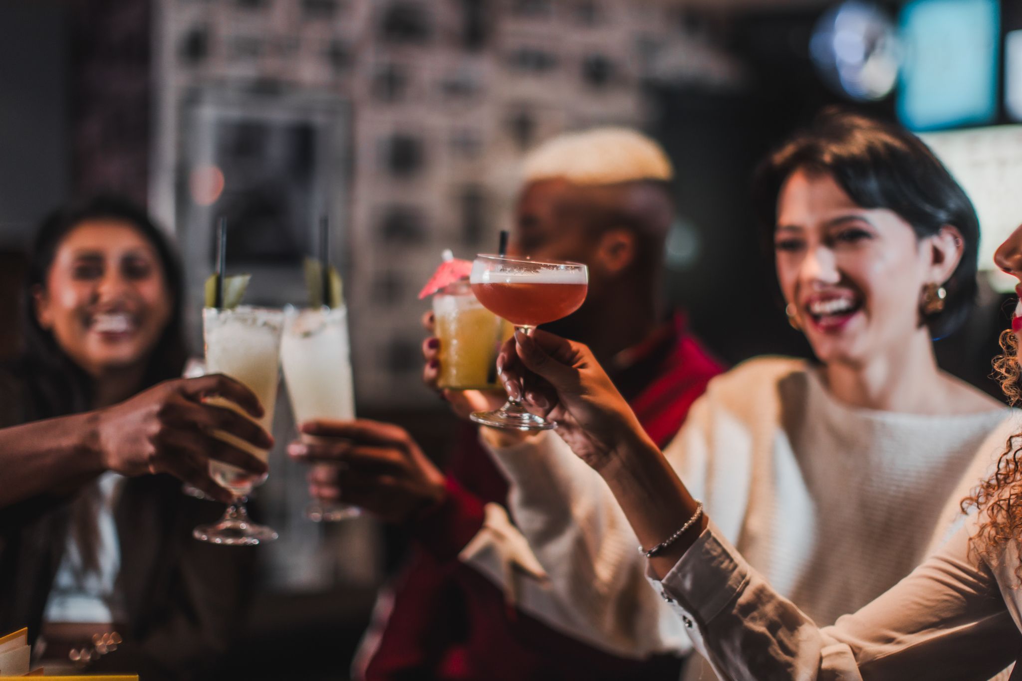 A diverse group of individuals joyfully toasting with drinks, celebrating a special occasion together.