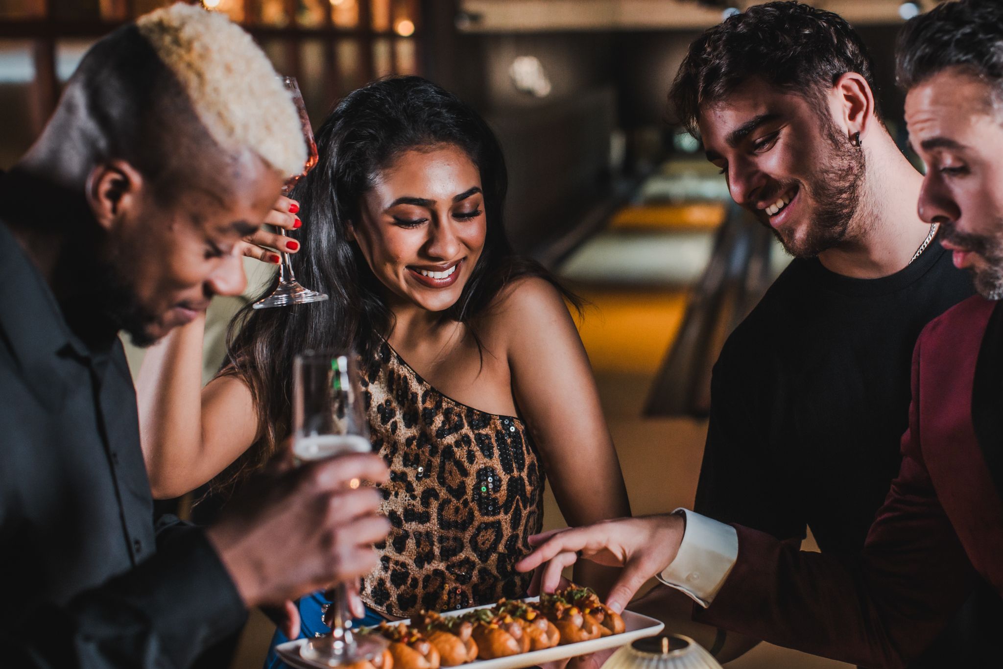 A lively group of friends sharing food and drinks while enjoying a fun bowling night together at the alley.