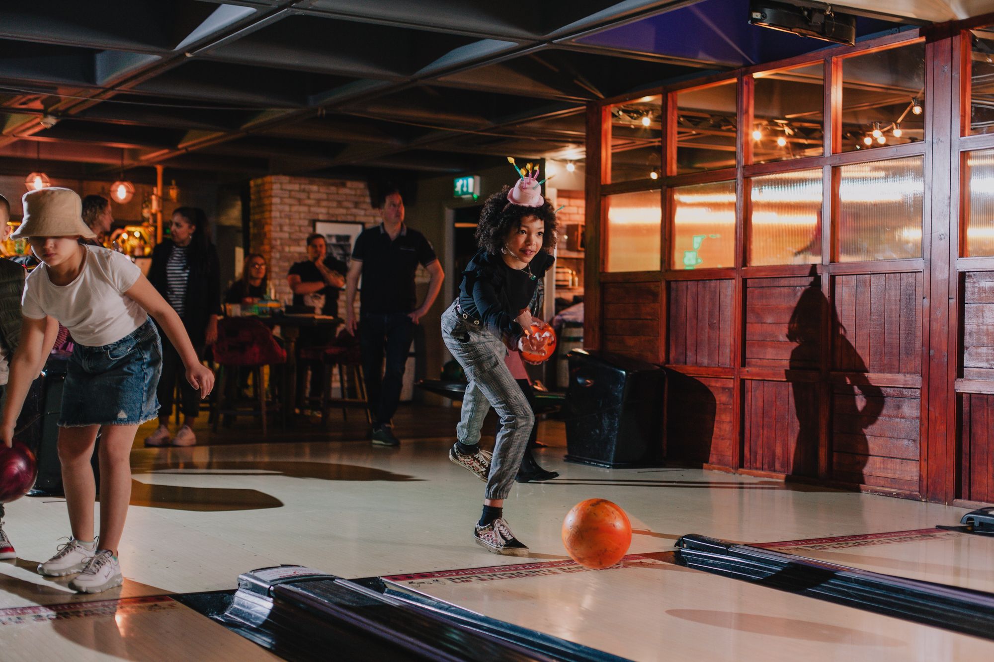 A young girl getting ready to bowl with a bowling ball in her hand.