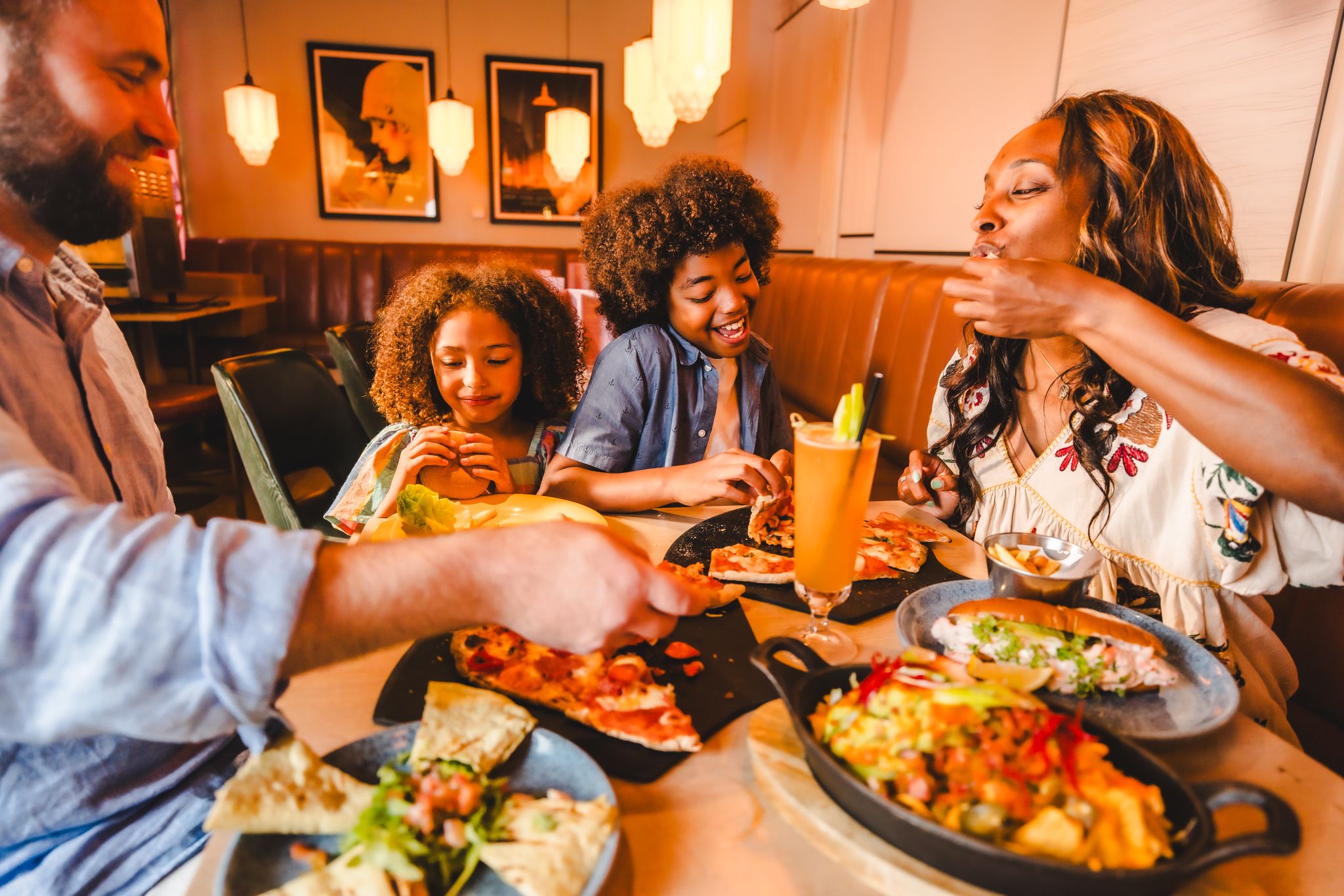 A diverse family eating different food items and smiling.